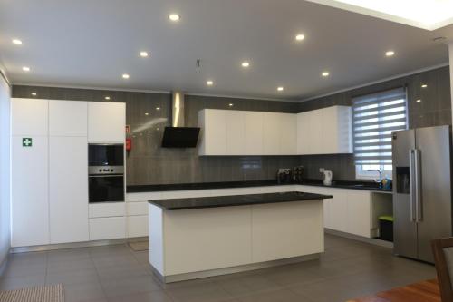 a kitchen with white cabinets and a black counter top at CASA DO ADRO -GRANEL in Nordeste