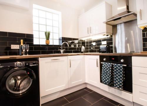 a kitchen with white cabinets and a washer and dryer at Kerns Cottage Stratford-upon-Avon in Stratford-upon-Avon