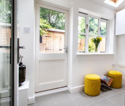 un pasillo con una puerta y dos taburetes amarillos en Kerns Cottage Stratford-upon-Avon en Stratford-upon-Avon