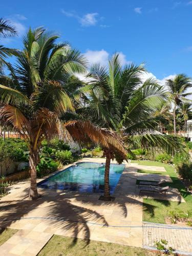a swimming pool with two palm trees next to it at Vila Saguaro in Trairi