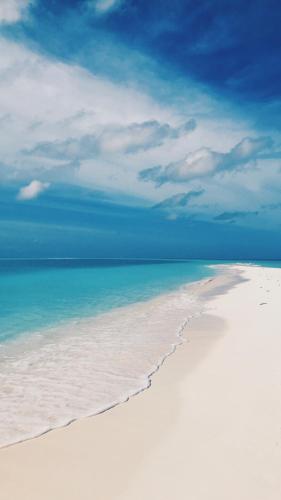 a white beach with the ocean and a blue sky at Summer Vibes Beach Front in Rasdu