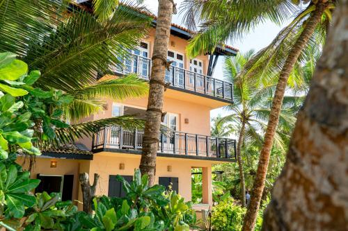 a building with palm trees in front of it at THE SLOW vegan hotel in Mirissa