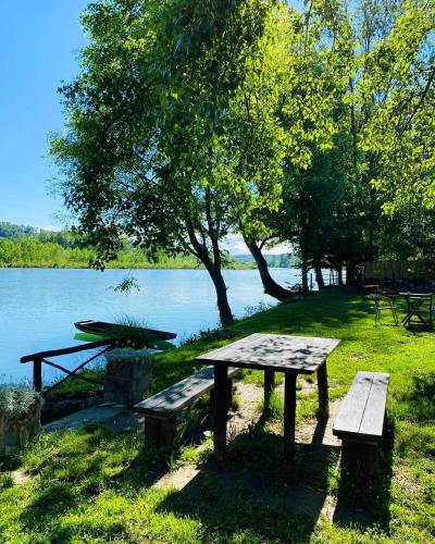 a picnic table and benches in front of a lake at Drinska laguna in Banja Koviljača