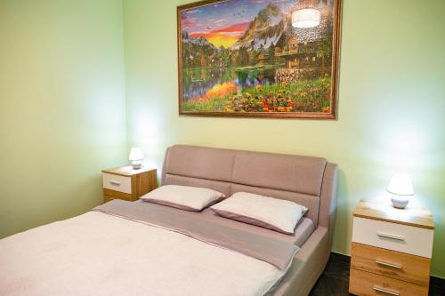 BIO Residence Apartments Timisoara في Uisenteş: غرفة نوم بسرير ودهان على الحائط