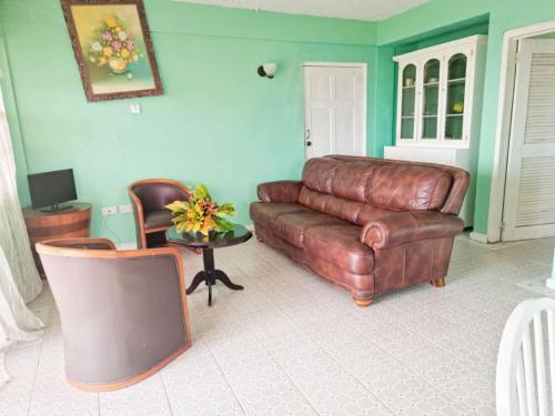 a living room with a leather couch and a table at Belle View Apartment Villa - Cactus in Laborie
