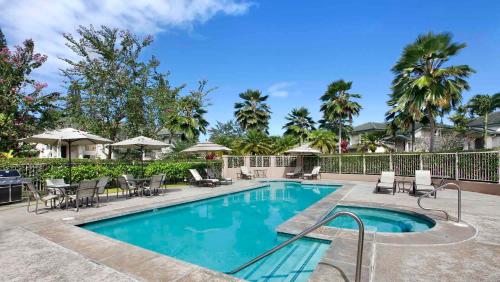 a swimming pool with chairs and umbrellas in a resort at Villas of Kamali'i Mountain Waterfall Views in Princeville
