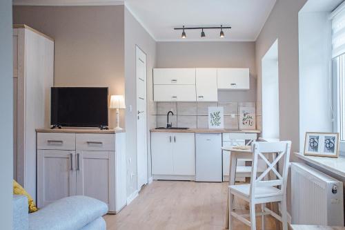 a kitchen with white cabinets and a tv in a room at Pod Słoneczną in Szczawno-Zdrój