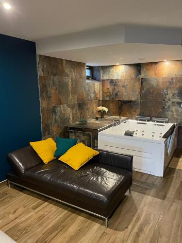 a living room with a black leather couch and a tub at Charmant logement avec balnéo in Wintzenheim