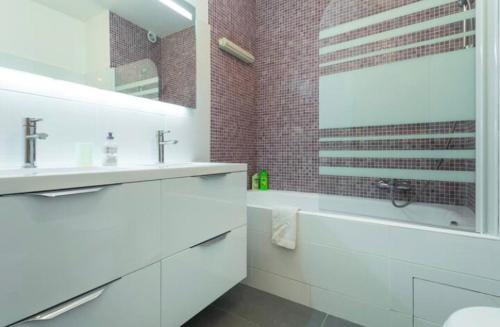 La salle de bains blanche est pourvue d'une baignoire, d'un lavabo et d'un miroir. dans l'établissement BIG WHITE, à Nice