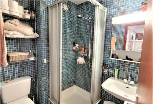 a blue tiled bathroom with a shower and a sink at Ferienwohnung Gemmiblick in Leukerbad