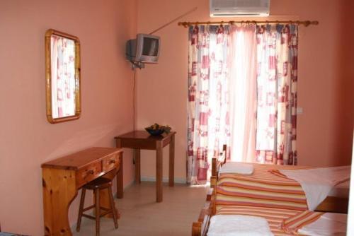 a bedroom with a bed and a desk and a window at Seashell Studios in Argasi