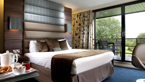 a hotel room with a bed and a balcony at Abbey Hotel Golf & Spa in Redditch