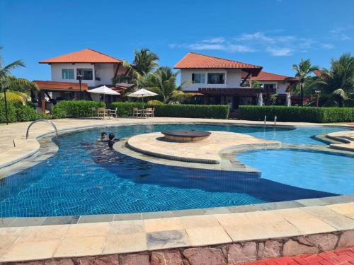 ein Pool in einem Resort mit Häusern im Hintergrund in der Unterkunft Flat Condomínio Beira-Mar in Tamandaré