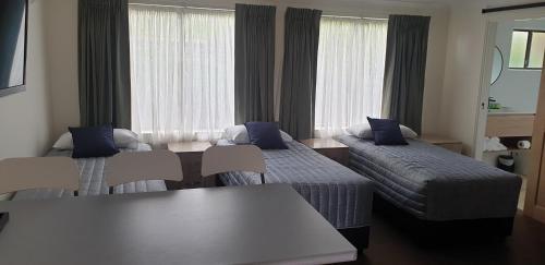 a hotel room with two beds and a table at Sandpiper Motel Ulladulla in Ulladulla
