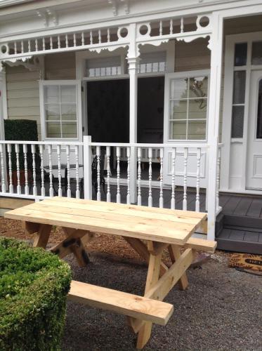 a wooden picnic table in front of a house at Aratahi Cottages - West Wing in Carterton