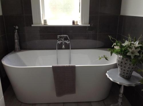 Aratahi Cottages - West Wing في Carterton: حوض استحمام أبيض في حمام مع نافذة