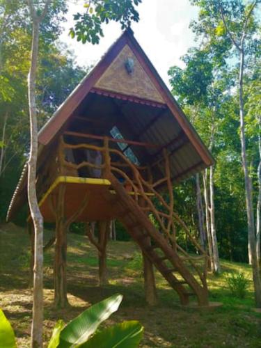 une cabane dans les arbres avec un escalier dans l'herbe dans l'établissement Treehouse Holidays-Open house, à Ko Yao Noi