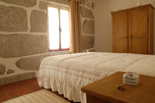 1 dormitorio con cama, ventana y mesa en Casa do Tear, en Macieira de Alcoba