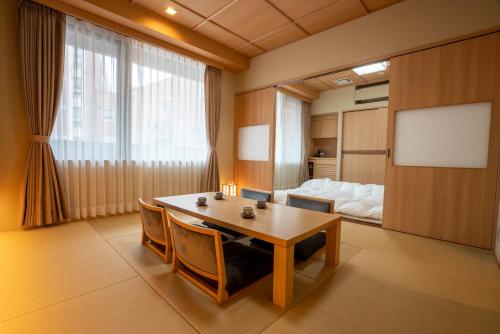 a room with a table and chairs and a bed at Kowakuen Haruka in Matsuyama