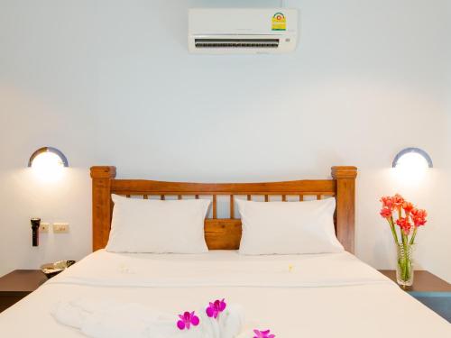 a bed with white sheets and purple flowers on it at Serenity Lakeside Resort in Kathu
