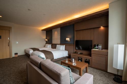 a hotel room with a bed and a couch at Kowakuen Haruka in Matsuyama