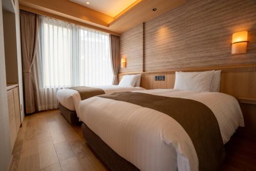 a hotel room with two beds and a window at Kowakuen Haruka in Matsuyama