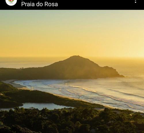 a view of a beach with a mountain in the distance at SUÍTES PRAIA DO ROSA in Imbituba