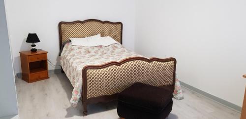 een slaapkamer met een bed, een stoel en een nachtkastje bij Centre ville Le Blanc Ville Basse in Le Blanc