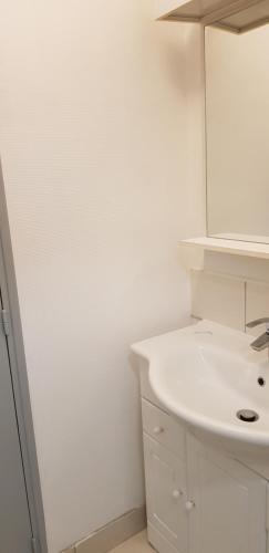 een witte badkamer met een wastafel en een spiegel bij Centre ville Le Blanc Ville Basse in Le Blanc