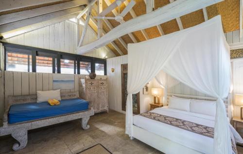 a bedroom with a bed and a canopy bed at Amed Lodge by Sudamala Resorts in Amed