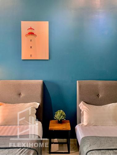 a bedroom with two beds and a blue wall at 9am-5pm, SAME DAY CHECK IN AND CHECK OUT, Work from Home, Comfy & Quiet Tamarind Suites-Cyberjaya by Flexihome-MY, in Cyberjaya