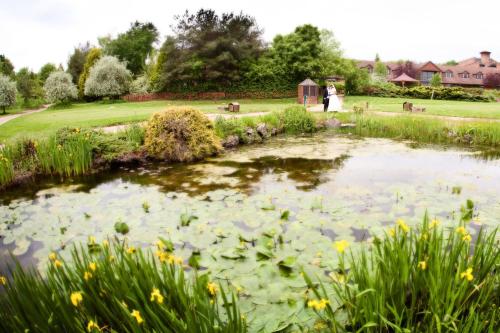 a pond in a garden with a woman in the background at Abbey Hotel Golf & Spa in Redditch