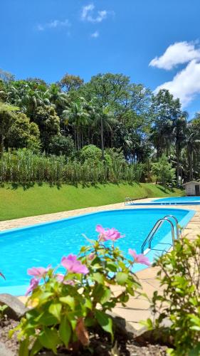 a swimming pool with pink flowers in front of it at Casa de campo Rosa dos ventos in Rodeio
