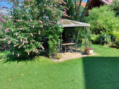 a garden with a table and a tree with pink flowers at Reginas Ferienhäuschen in Krieglach