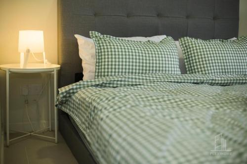 a bed with a green and white checked comforter and a lamp at 9am-5pm, SAME DAY CHECK IN AND CHECK OUT, Work from Home, Comfy & Quiet Tamarind Suites-Cyberjaya by Flexihome-MY, in Cyberjaya