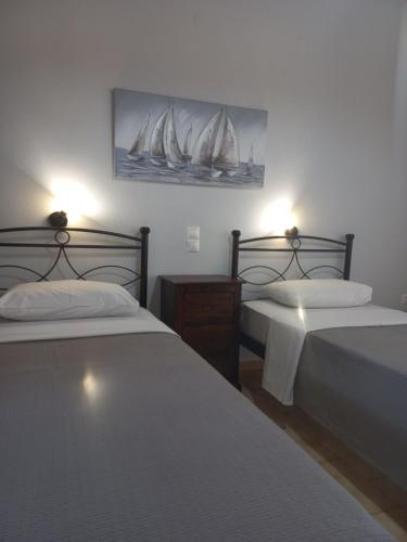 a bedroom with two beds with white sheets and sailboats on the wall at Dennis L studios in Laganas