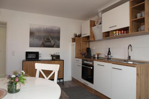 a kitchen with white cabinets and a table and a sink at Gästehaus zum Rhein in Rheinhausen