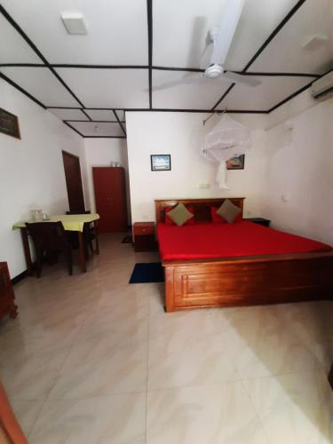 a bedroom with a red bed and a table at Susee Villa in Bentota