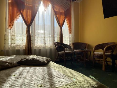 um quarto com uma cama e cadeiras e uma janela em Pensiunea Crocus - Sauna & Billiard em Poiana Brasov