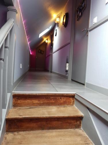 a hallway with purple walls and a wooden stair case at Hotel restaurant La Pêcherie - Le manoir d'à coté - Les 5 ruches -Logis hôtels in Courseulles-sur-Mer
