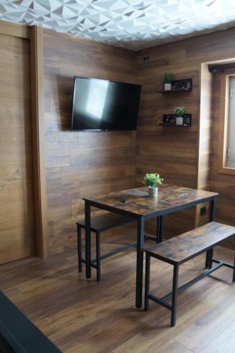 a room with a table and a tv on a wall at ROYAL SUITE TOTTO'NETTA 504 in Passo del Tonale