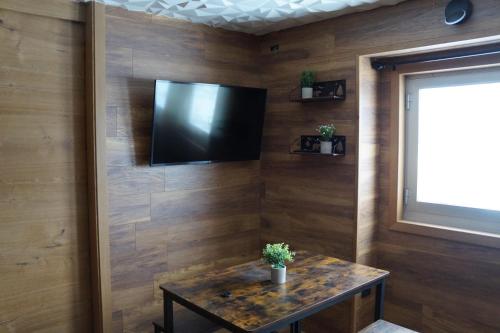a room with a table and a tv on a wall at ROYAL SUITE TOTTO'NETTA 504 in Passo del Tonale
