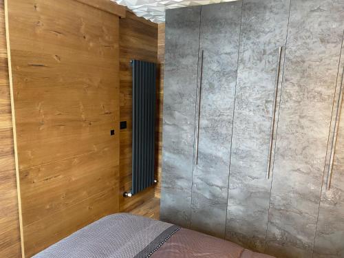 a bedroom with a bed and wooden walls at ROYAL SUITE TOTTO'NETTA 504 in Passo del Tonale