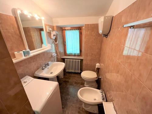ein Badezimmer mit einem Waschbecken, einem WC und einem Spiegel in der Unterkunft Hotel La Torretta in Assisi