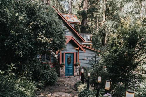 a small house with a blue door in the woods at Wild Orchid Olinda Private Luxury Cottage in Olinda