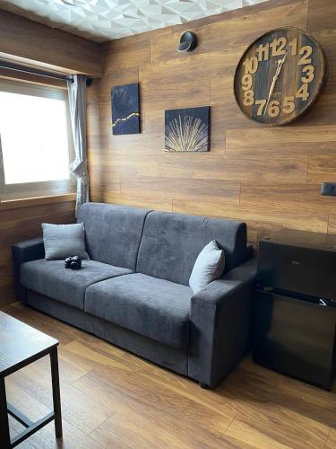 a living room with a couch and a clock on the wall at ROYAL SUITE TOTTO'NETTA 504 in Passo del Tonale