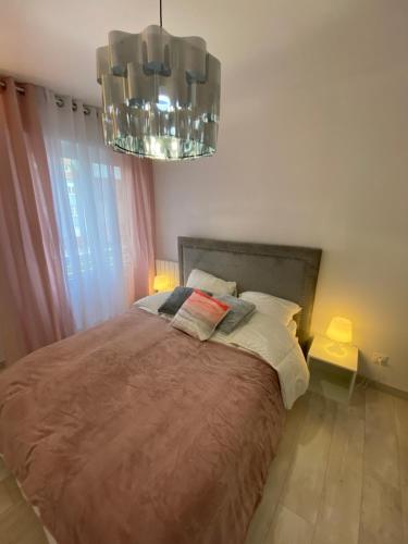 une chambre avec un grand lit et un lustre dans l'établissement Le Grand DOLLFUS, 90m2 de charme au coeur de ville, à Mulhouse