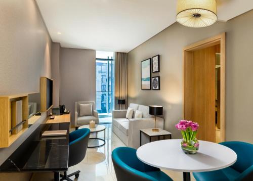 a living room with a table and blue chairs at Millennium Place Mirdif in Dubai