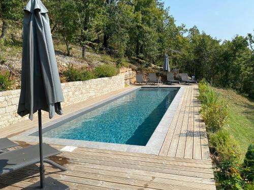 - une piscine avec un parasol à côté d'une terrasse en bois dans l'établissement Villa Durandal, à Souillac
