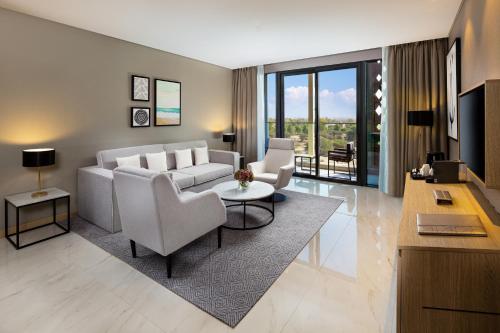 a living room with a couch and chairs and a television at Millennium Place Mirdif in Dubai